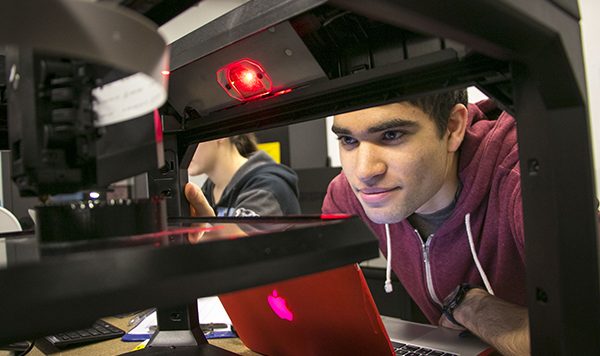 Student peers at the 3D printer output