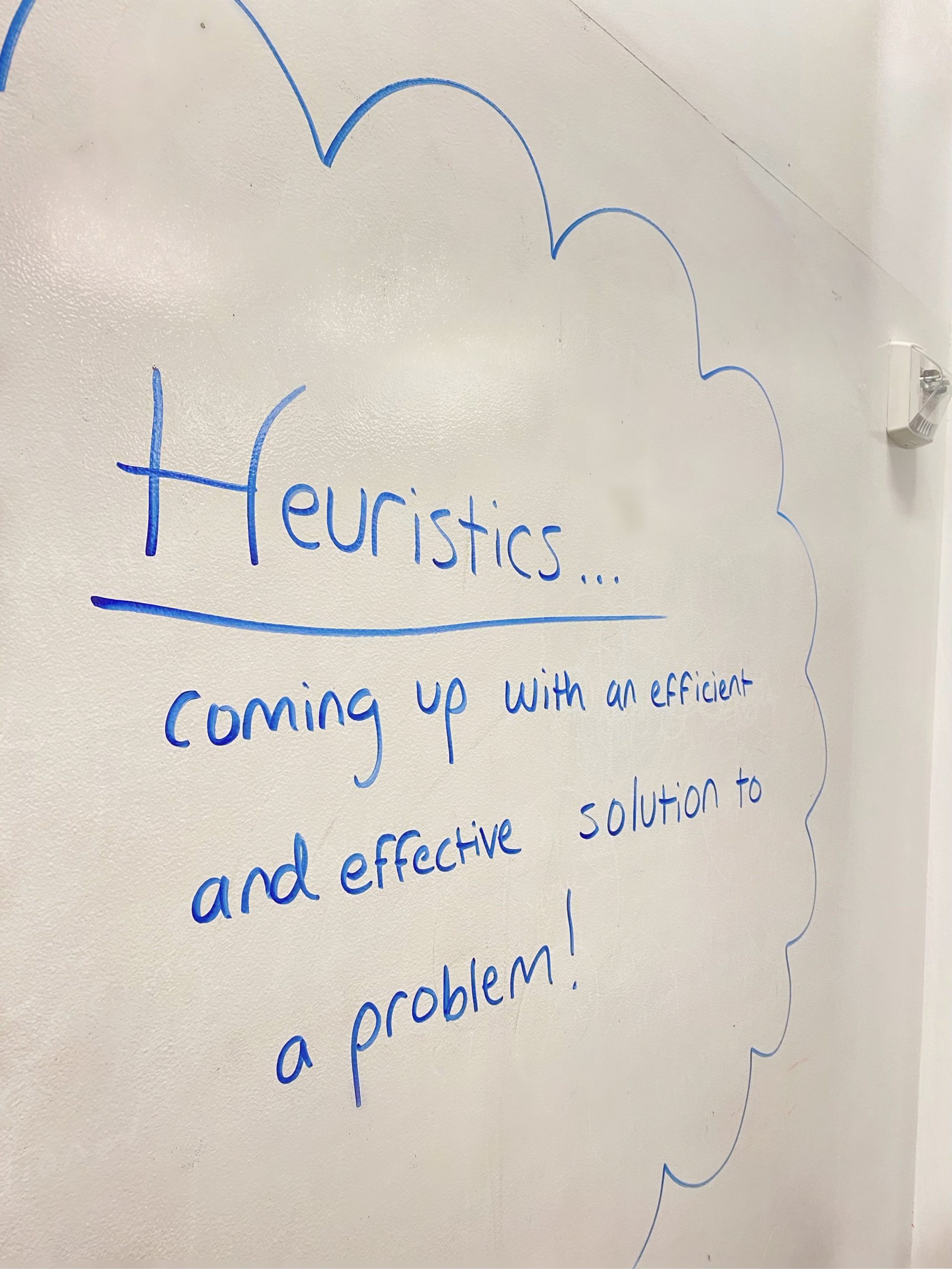 Whiteboard with heuristics notes written in blue whiteboard marker