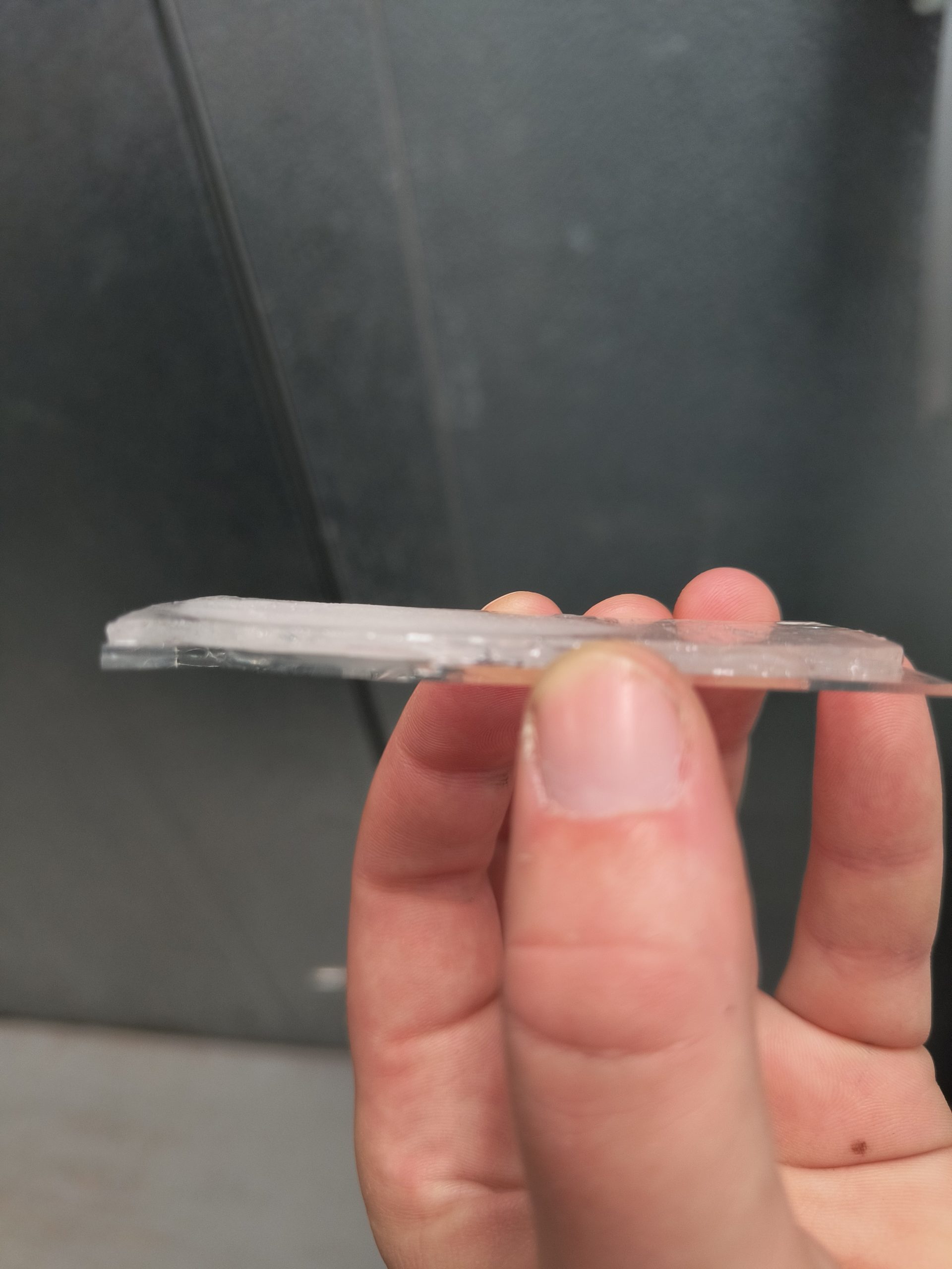 A hand holds up an ice sample on a specimen slide, both of which are only a few millimeters thick