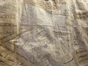 A printed textile shows a composite image of many layers of handwritten notes