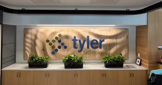 A large wooden sign with blue and green lettering is mounted to a wall over a line of cabinets. Three potted plants sit on top of the cabinets. The surface of the sign has ripples like the surface of water when a stone is dropped in.